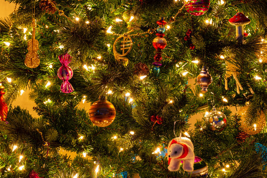 Christmas tree decorations of red and gold closeup with yellow lights and yellow background