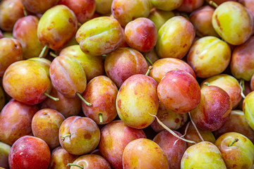 A full frame photograph of ripe plums for sale on a market stall