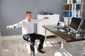 Businessman Exercising With Dumbbells