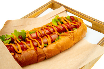 Hot dog with salad and cucumbers with tomato ketchup and mustard on white background. Tasty and beautiful fast food on a light back.
