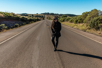 Modelo posando no meio de uma estrada deserta