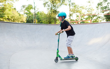 A boy on a scooter and in protective helmet do incredible stunts in skate park. Extreme jump. The concept of a healthy lifestyle and sports leisure © oes
