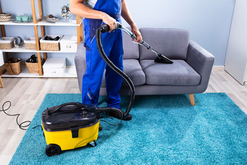 Man Cleaning Sofa With Vacuum Cleaner