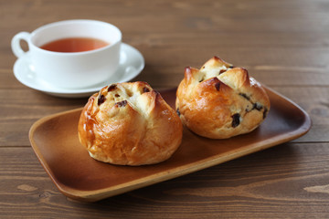 お皿にのせた レーズン パン 紅茶 木のテーブル