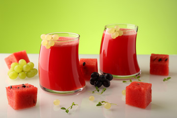 Freshly squeezed watermelon juice, with square slices of watermelon, decorated with bunches of grapes.