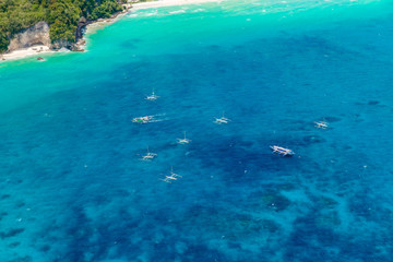 Aerial view from the drone on the landscape tropical sand beach with palm trees and turquoise sea with boats. Summer vacation concept.
