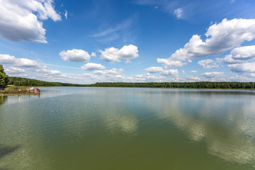 pier on the shore of a large lake in summer day with beautiful clouds.  sky reflection