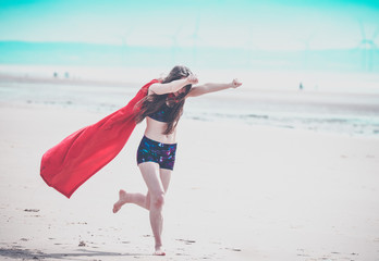 pretty girl on the beach with super hero cape