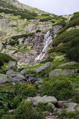 Fototapeta na wymiar Mountain waterfall in High Tatras (Skok). Tall rocks covered with scrub.