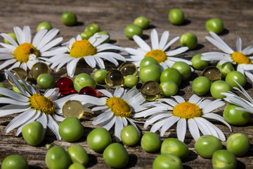 Chamomile green peas and vitamin capsules on an old wooden table Выделите текст, чтобы посмотреть примеры