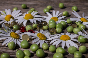 Chamomile green peas and vitamin capsules on an old wooden table Выделите текст, чтобы посмотреть примеры