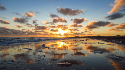 Fototapeta na wymiar Golden clouds reflecting in the sea water on the coast
