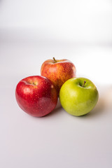 Red, green, and orange red delicious, granny smith, and fuji apples in a group isolated against a white background