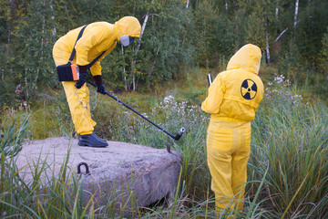 Two dosimetrist  in protective suite and mask with geiger counter measuring radiation level in danger zone - 285729084