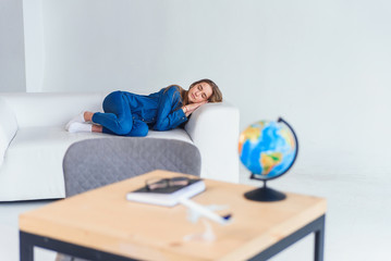 Tired young female student in casual clothing sleeps on white sofa. Beautiful woman resting after...