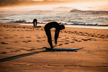 A surfer is stretching and getting ready to surf the waves at a beach
