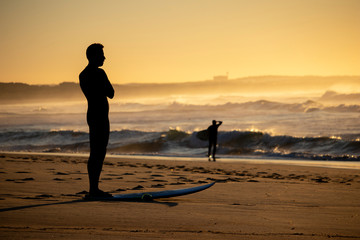A surfer is stretching and getting ready to surf the waves at a beach
