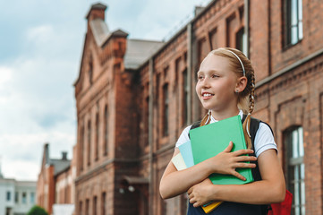 Portrait of schoolgirls with books in their hands. Against the background of an old building. Back to school concept.