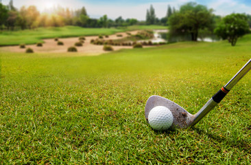 White Golf ball on tee ready to be shot on blurred beautiful landscape of golf course in bright day time with copy space. Sport, Recreation, Relax in holiday concept.