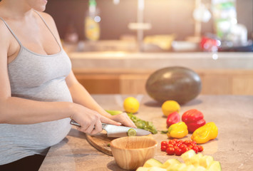 Eat well, live well. Young pregnant woman is preparing a salad. Copy space in upper part