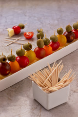 Party snacks with yellow cheese, cherry tomato and olives.