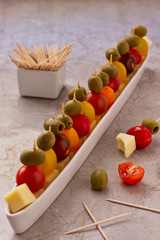 Party snacks with yellow cheese, cherry tomato and olives.