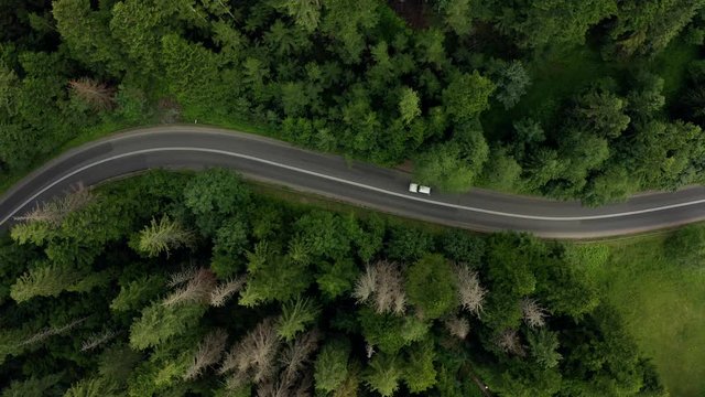4K. Aerial view of a mountain serpentine road with buses and cars traveling along a zigzag road in the mountains of Poland. Curvy switchback highway with hairpin turns snaking through the woods.