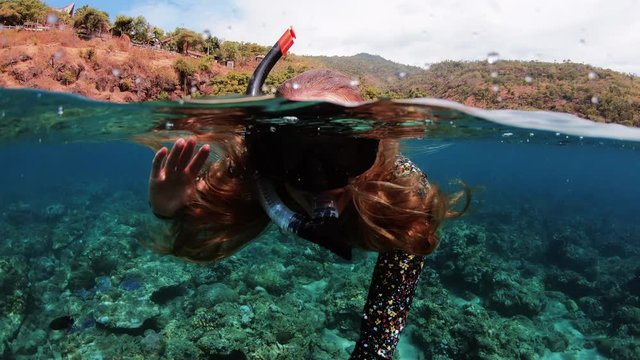 Happy Snorkelling Girl Waving to Camera Underwater in Tropical Destination, 50-50 dome split slow motion