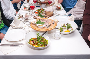 People sit at the festive table with food and drinks in the restaurant