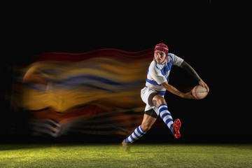 New star of the competitive. One caucasian man playing rugby on the stadium in mixed light. Fit young male player in motion or action during sport game. Concept of movement, sport, healthy lifestyle.