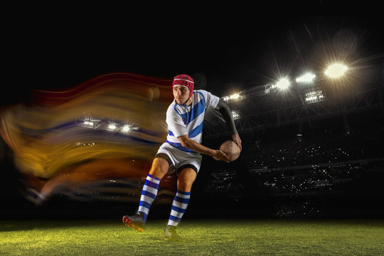 New star of the competitive. One caucasian man playing rugby on the stadium in mixed light. Fit young male player in motion or action during sport game. Concept of movement, sport, healthy lifestyle. - Powered by Adobe