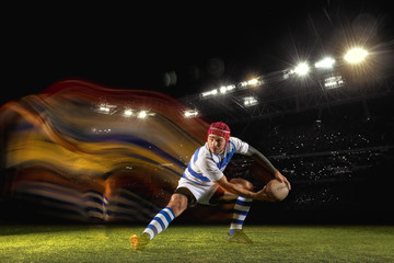 Fototapeta na wymiar Ready for winning. One caucasian man playing rugby on the stadium in mixed light. Fit young male player in motion or action during sport game. Concept of movement, sport, healthy lifestyle.