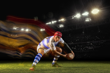 Ready for winning. One caucasian man playing rugby on the stadium in mixed light. Fit young male player in motion or action during sport game. Concept of movement, sport, healthy lifestyle.