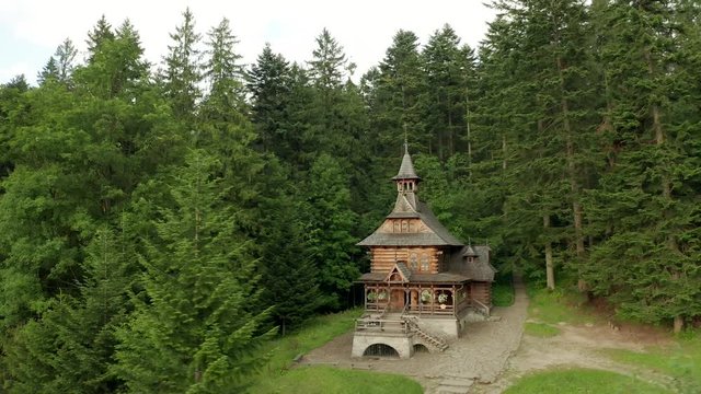 Drone shot at an old wooden church in a coniferous forest. Suburb of Zakopane in Poland.