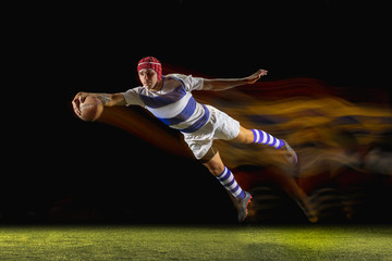 Ready to fly for win. One caucasian man playing rugby on the stadium in mixed light. Fit young male...