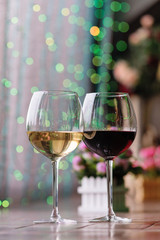 Two glasses of wine white and red standing on a table. Colorful bokeh. Wine tastings, wine tour. Cold toning. Concept alcoholic drinks. 