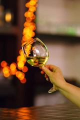 Hand sommelier holding glass of white wine. Wine-tasting. White wine concept. Wine tour. Vertical, warm toning. Free space for text.