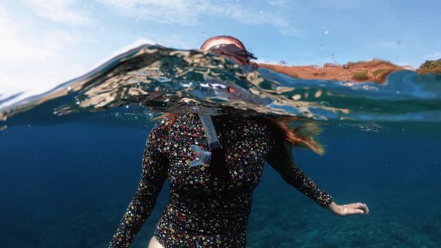 Happy Snorkelling Girl Waving to Camera Underwater in Tropical Destination with Coral Reef Below, 50-50 dome split slow motion