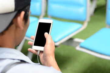 A man uses a smartphone while sitting and waiting. Passenger waiting point