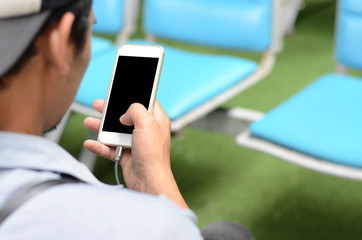 A man uses a smartphone while sitting and waiting. Passenger waiting point