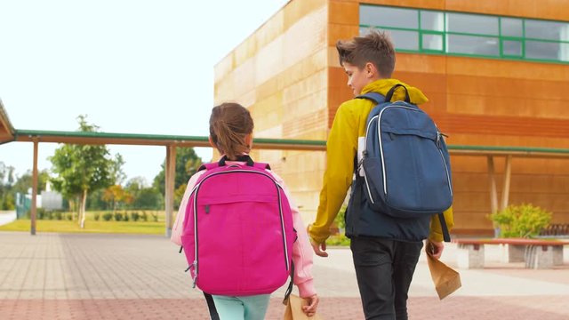 education, childhood and people concept - children with backpacks going to school with lunch in paper bags