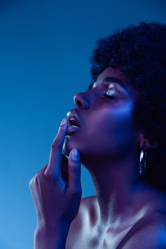 Marvelous night. Portrait of female fashion model in neon light on gradient background. Beautiful african woman with trendy make-up and well-kept skin. Vivid style, beauty, cosmetics concept.