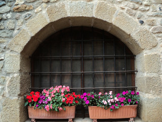 Fototapeta na wymiar Potted flowers in a window of a stone building. Comfort and warmth.