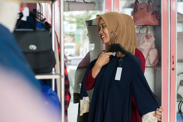 portrait of an attractive young asian muslim woman shopping in a fashion strore