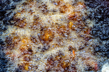 Boiling oil in frying pan for cooking. Thai street vendor sells grilled chicken legs meat at street food market in Thailand. Frying chicken legs in a pan close up