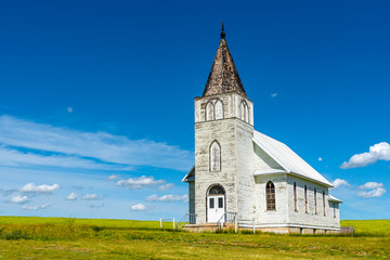 Fototapeta na wymiar The historic Immanuel Lutheran Church in Admiral, Saskatchewan with a canola field in the background