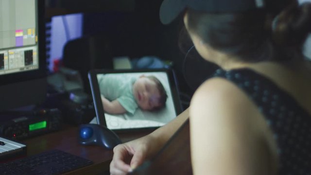 Slow motion of woman playing guitar while checking baby on baby monitor