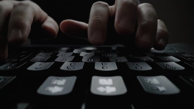 Close-up man typing on computer keyboard with hands and fingers. Macro soft focus dolly shot. Computer programming, text chat online messaging and online marketing business concept.
