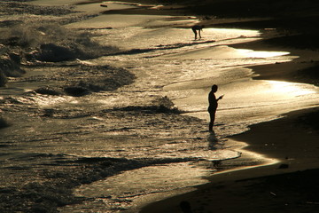 夕日に映る海岸の人