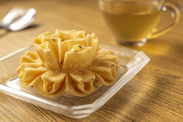 Crispy lotus blossom cookie or Dok Jog on the wooden table background of Thai desserts. Thai traditional snack.